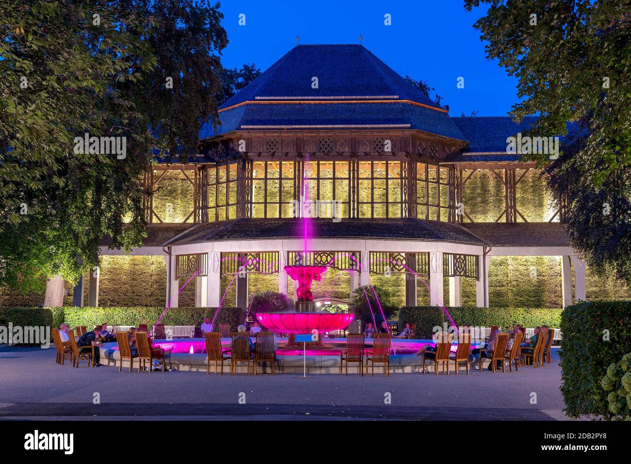 Spa giardino illuminazione nel giardino termale reale Bad Reichenhall. La fontana illuminata Solebrunnen di fronte alla casa di laurea. Bad Reichenhall, Baviera, Germania Foto Stock