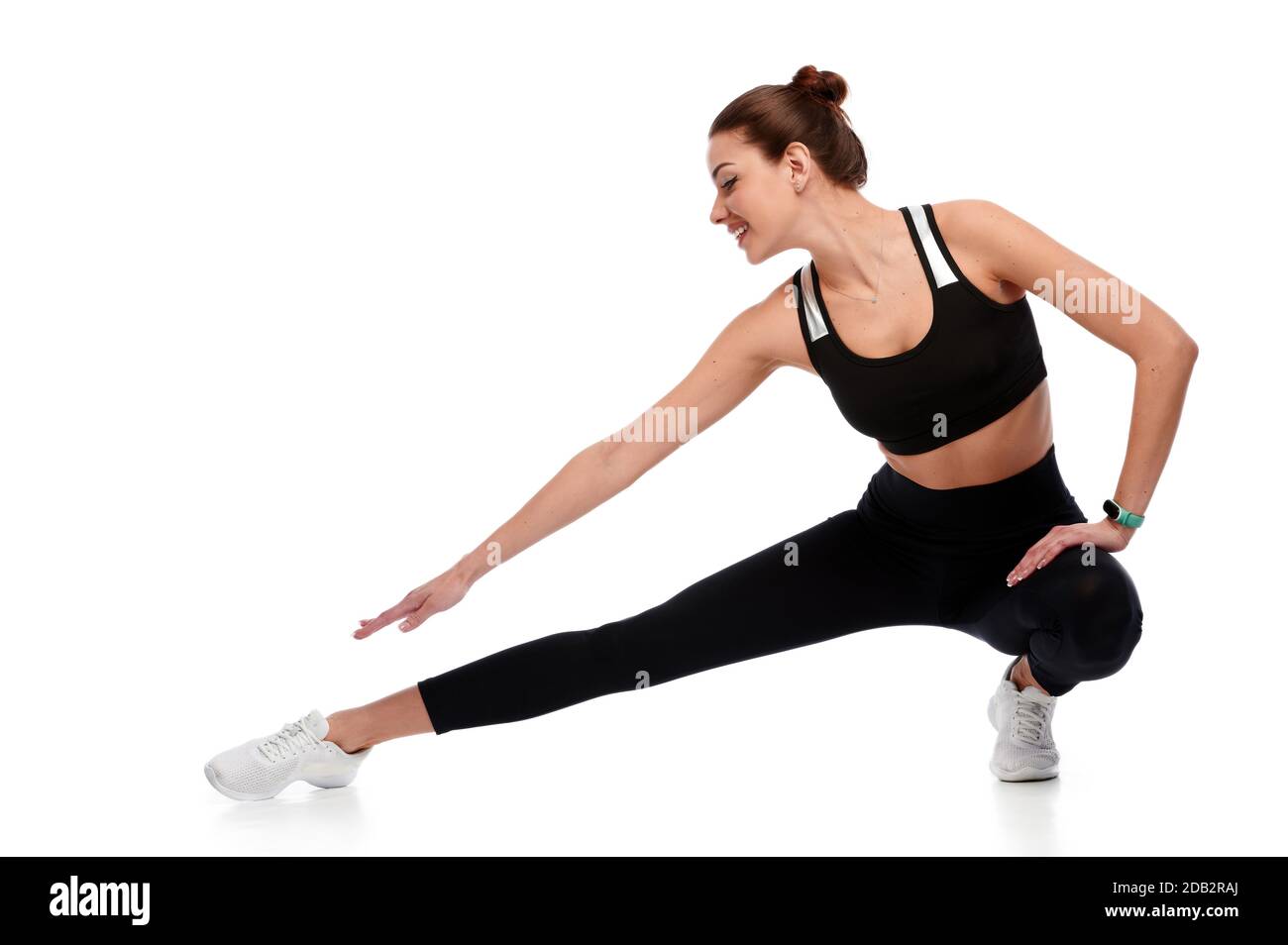 Calzare donna fitness forte in sportswear gambe stretching su sfondo bianco isolato. Istruttore di sport femminile che fa esercizio fisico Foto Stock