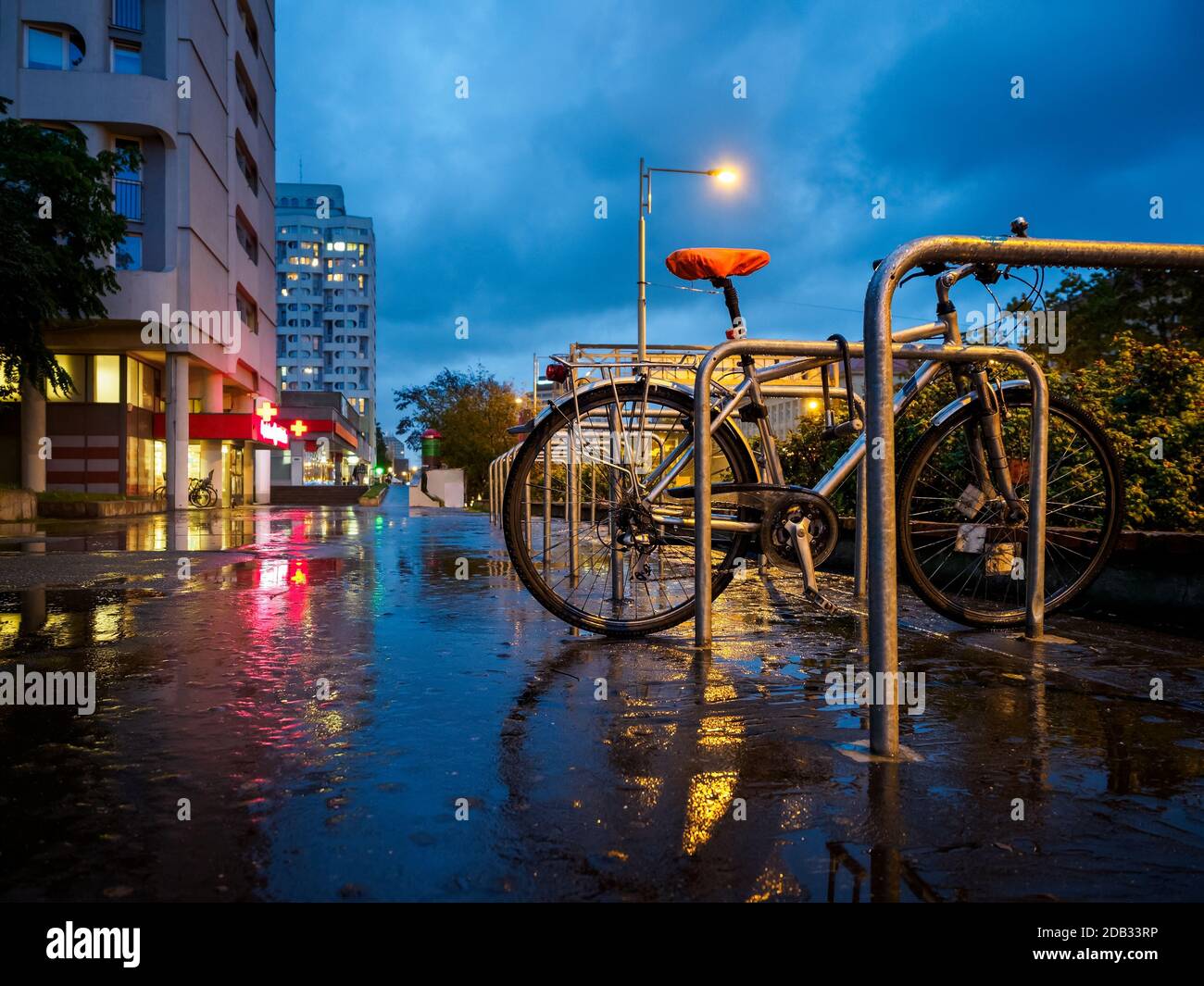 una bicicletta è rimasta sulla strada della città piovosa di notte Foto Stock