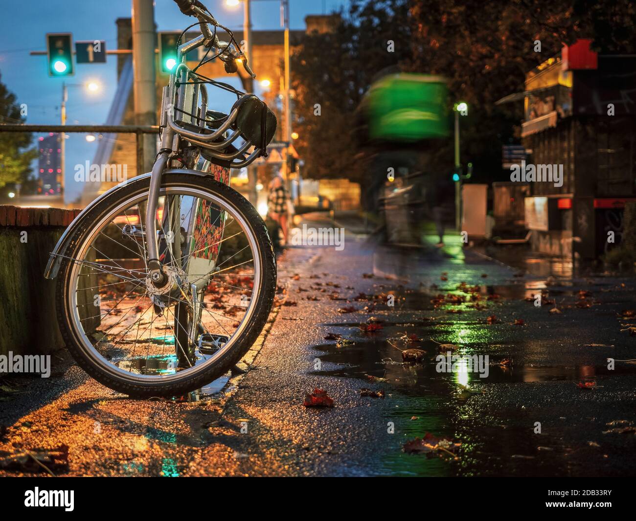 una bicicletta è rimasta sulla strada della città piovosa di notte Foto Stock