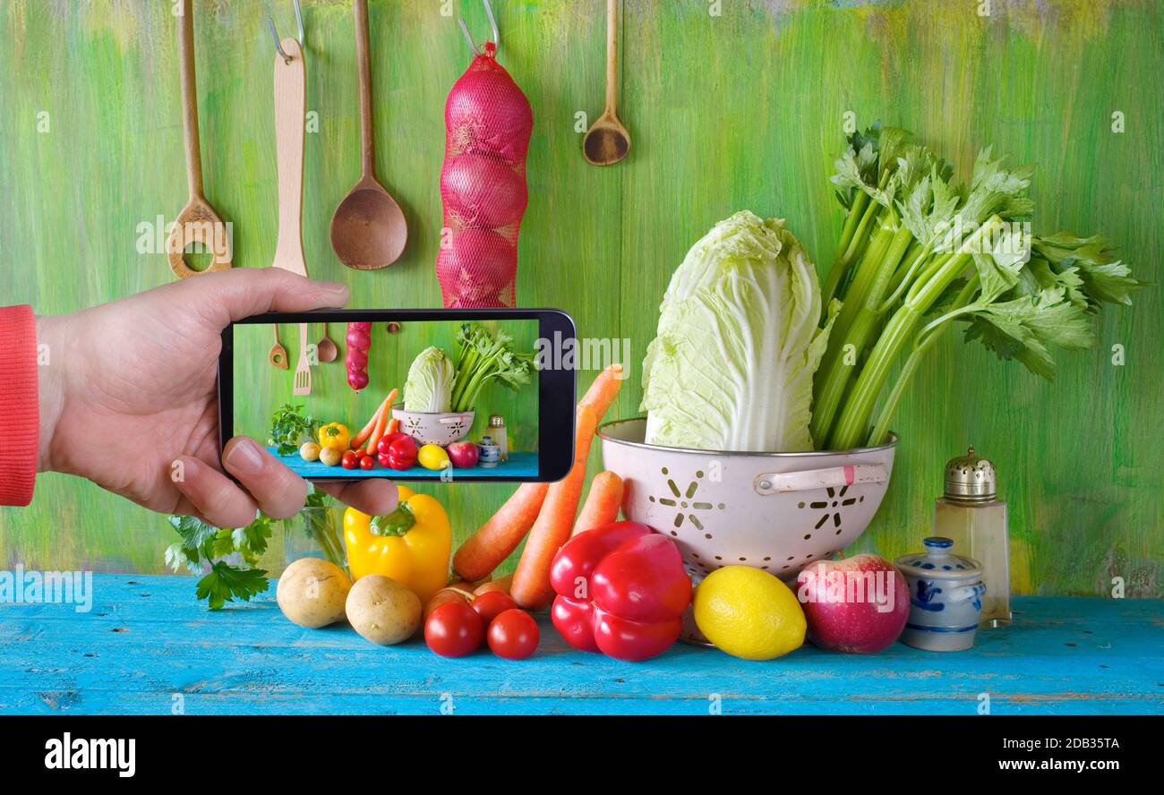scattare una foto con uno smartphone di ingredienti alimentari biologici, verdure, utensili da cucina, sano concetto di consumo Foto Stock