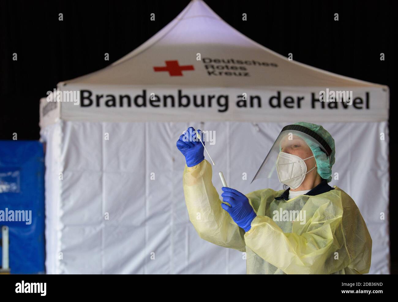 Potsdam, Germania. 16 Nov 2020. Di fronte alla tenda nella stazione di prova della corona appena aperta nel foyer del Metropolitishalle del Filmpark Babelsberg, un dipendente del DRK dimostra la procedura di un test di striscio per un test della corona. L'Kassenärztliche Vereinigung Brandenburg (KVBB) e il DRK hanno istituito il centro per alleviare gli oneri che gravano sui medici residenti nella regione. I pazienti per il test corona richiedono un rinvio da parte di un medico e un appuntamento per un test striscio. Credit: Soeren Stache/dpa-Zentralbild/dpa/Alamy Live News Foto Stock