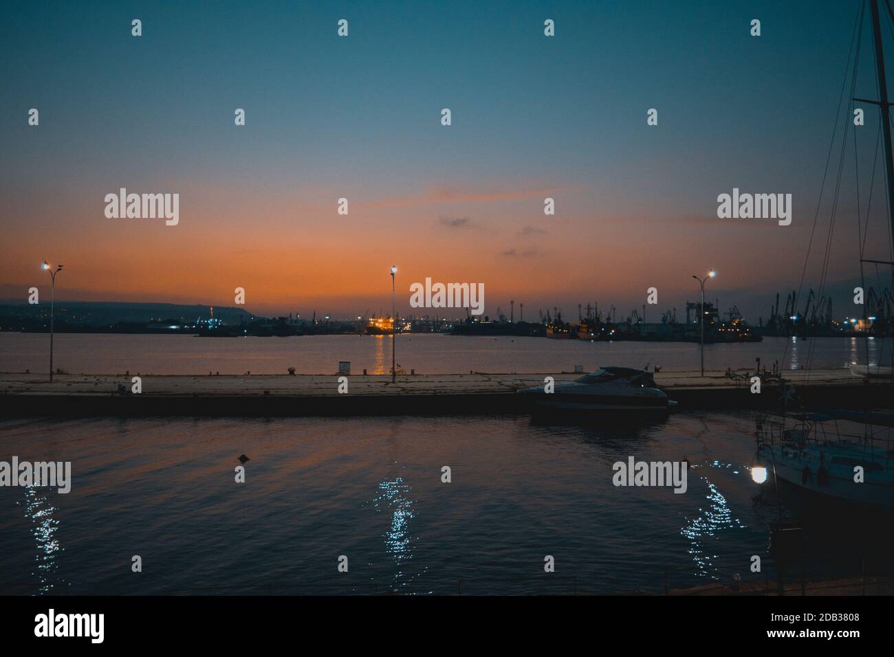 Paesaggio tramonto combinato con luci che si riflettono nel mare e alcune barche. Foto Stock