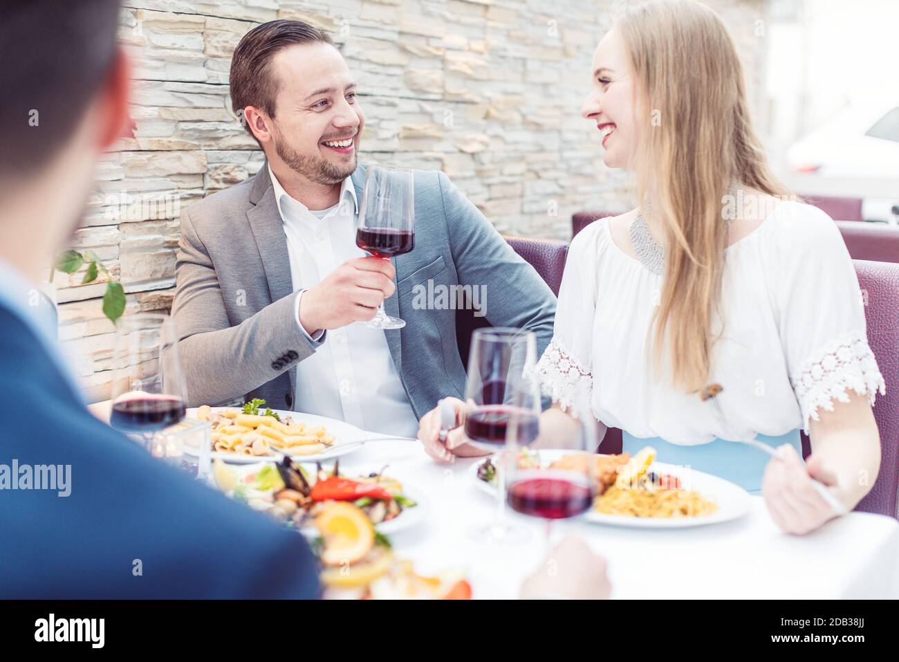 Persone in un ristorante italiano bere vino e mangiare pasta di buon umore Foto Stock