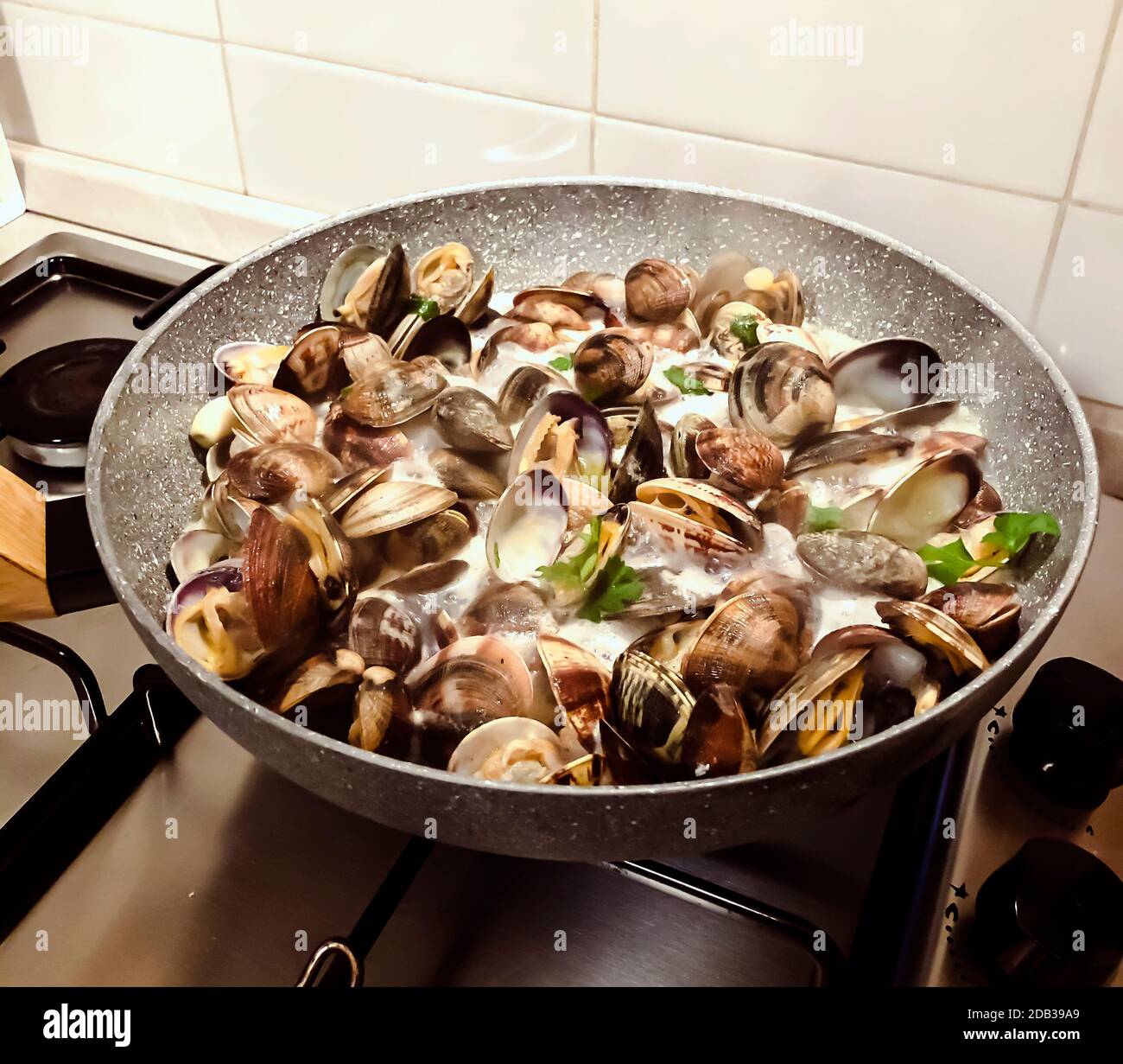 cuocere le vongole in una padella di pietra con prezzemolo e vino bianco.  Cucina e ricette del ristorante. Frutti di mare shell Foto stock - Alamy