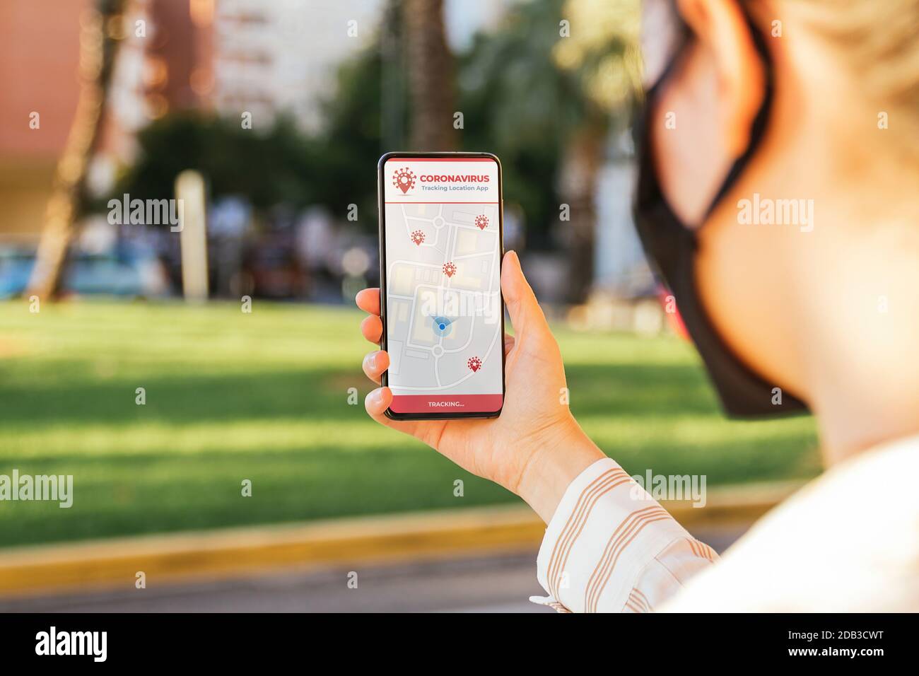Stock foto di una giovane donna utilizzando un Coronavirus tracking app sul suo telefono mentre è in strada Foto Stock