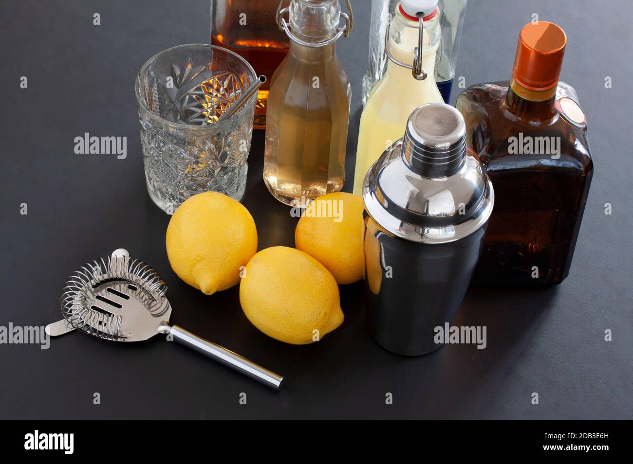 Accessori barra visti dall'alto. Strumenti per bevande e ingredienti per cocktail, tra cui shaker, setaccio, bicchiere, liquore, bottiglie di sciroppo fatte in casa e tre lem Foto Stock