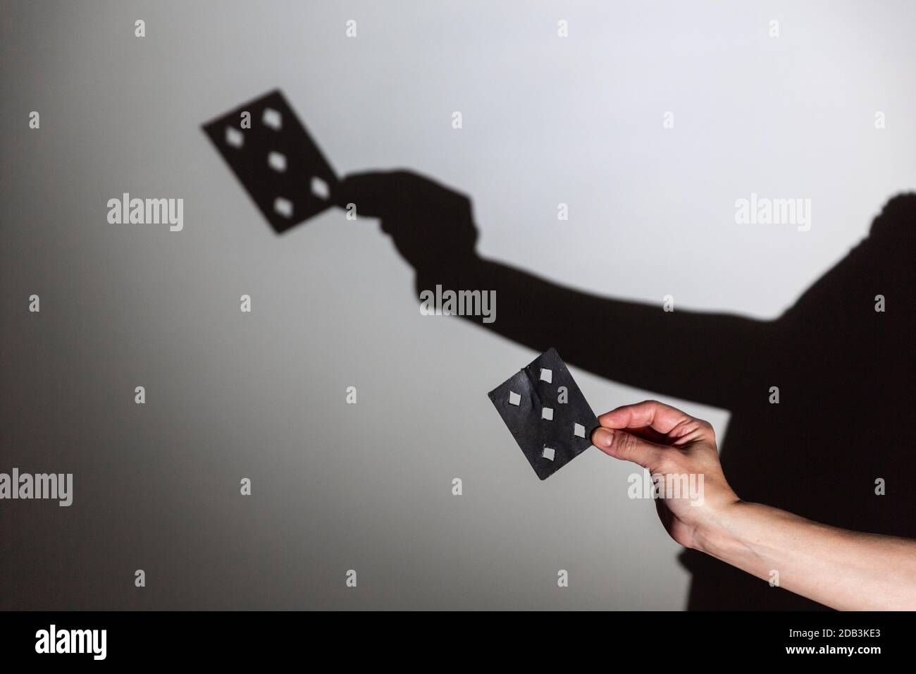 riproduci l'ombra proiettata su uno schermo bianco. le mani della persona modellano una carta per un trucco magico Foto Stock