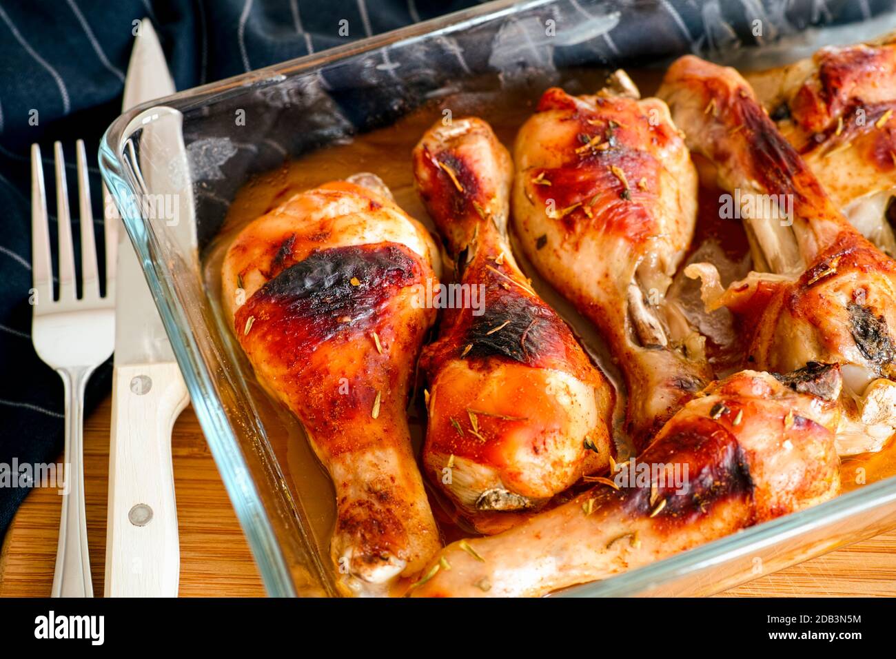 Cosce di pollo arrosto in teglia da forno in vetro, forchetta, coltello e  tovagliolo nero sul tavolo Foto stock - Alamy