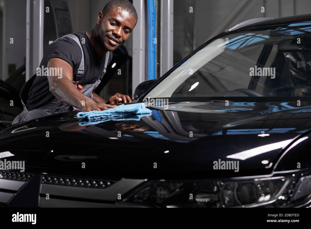 giovane adulto afro americano uomo auto di pulizia con panno microfibra, dettagli auto o concetto di valeting Foto Stock