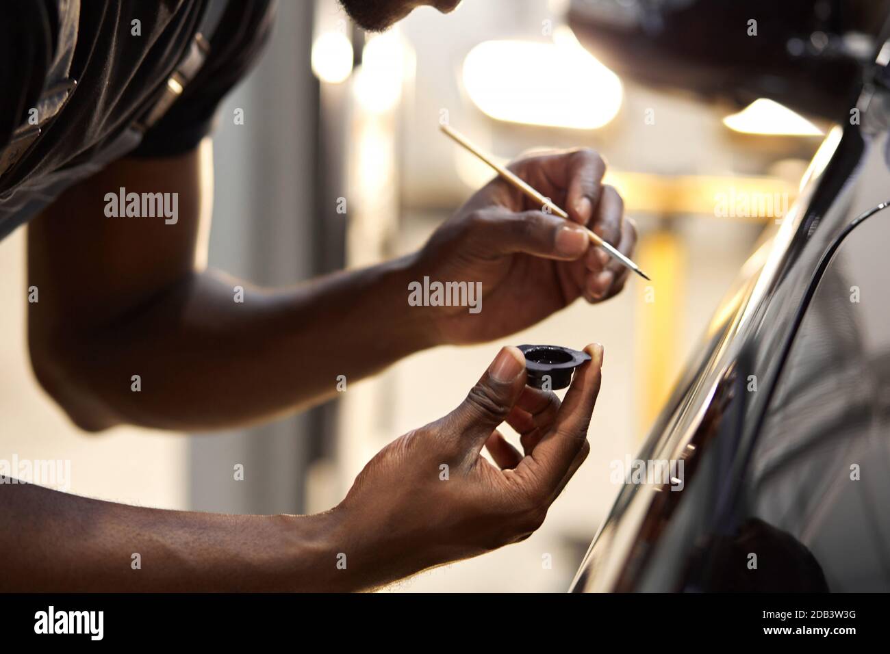 le mani dell'uomo africano usano la spazzola di dettaglio per verniciare l'automobile o per pulire e rimuovere lo sporco, i particolari dell'automobile e il concetto di pittura di lavaggio dell'automobile. primo piano, maschio corto Foto Stock