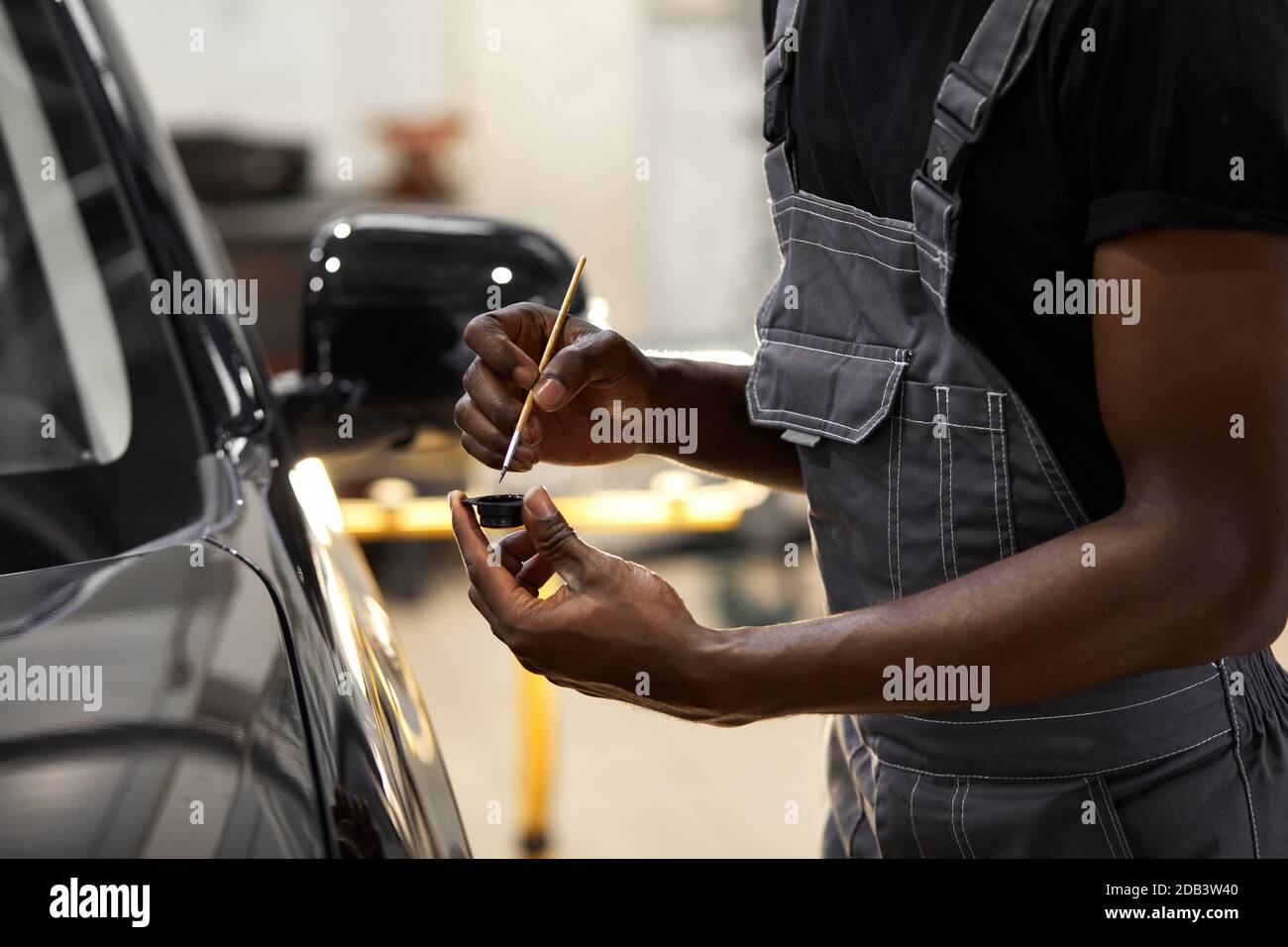 le mani dell'uomo africano usano la spazzola di dettaglio per verniciare l'auto o per pulire e rimuovere lo sporco, i dettagli dell'auto e il concetto di pittura di autolavaggio Foto Stock
