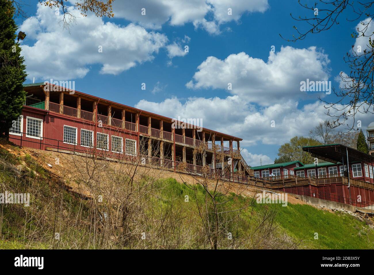 Vecchi edifici di fattoria rossa sulla cima di una collina sotto il bel cielo blu con nuvole soffici Foto Stock
