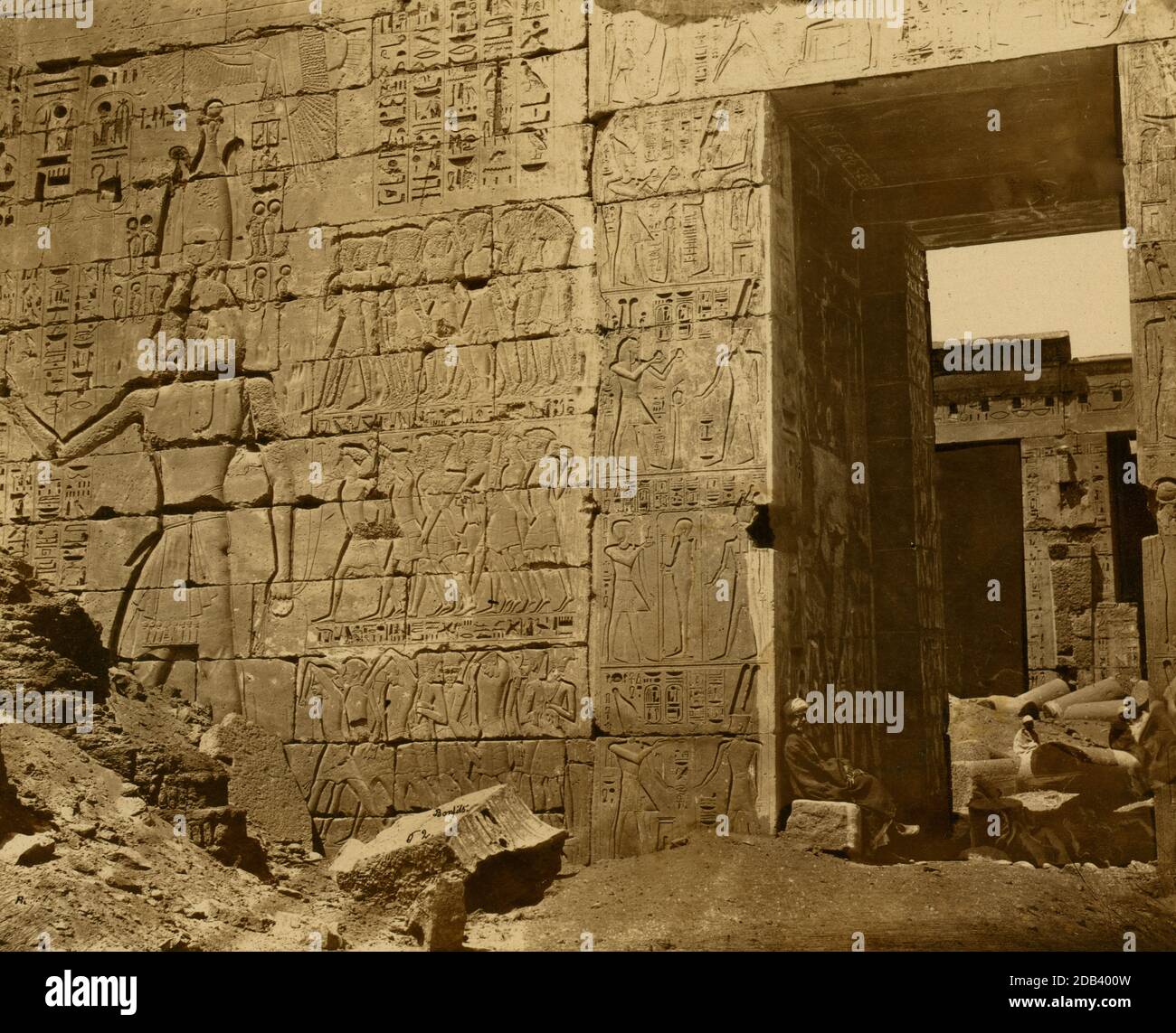 Muro del tempio con geroglifici e ingresso, macerie dentro e fuori, sito di Medinet Habu, Egitto. Foto Stock