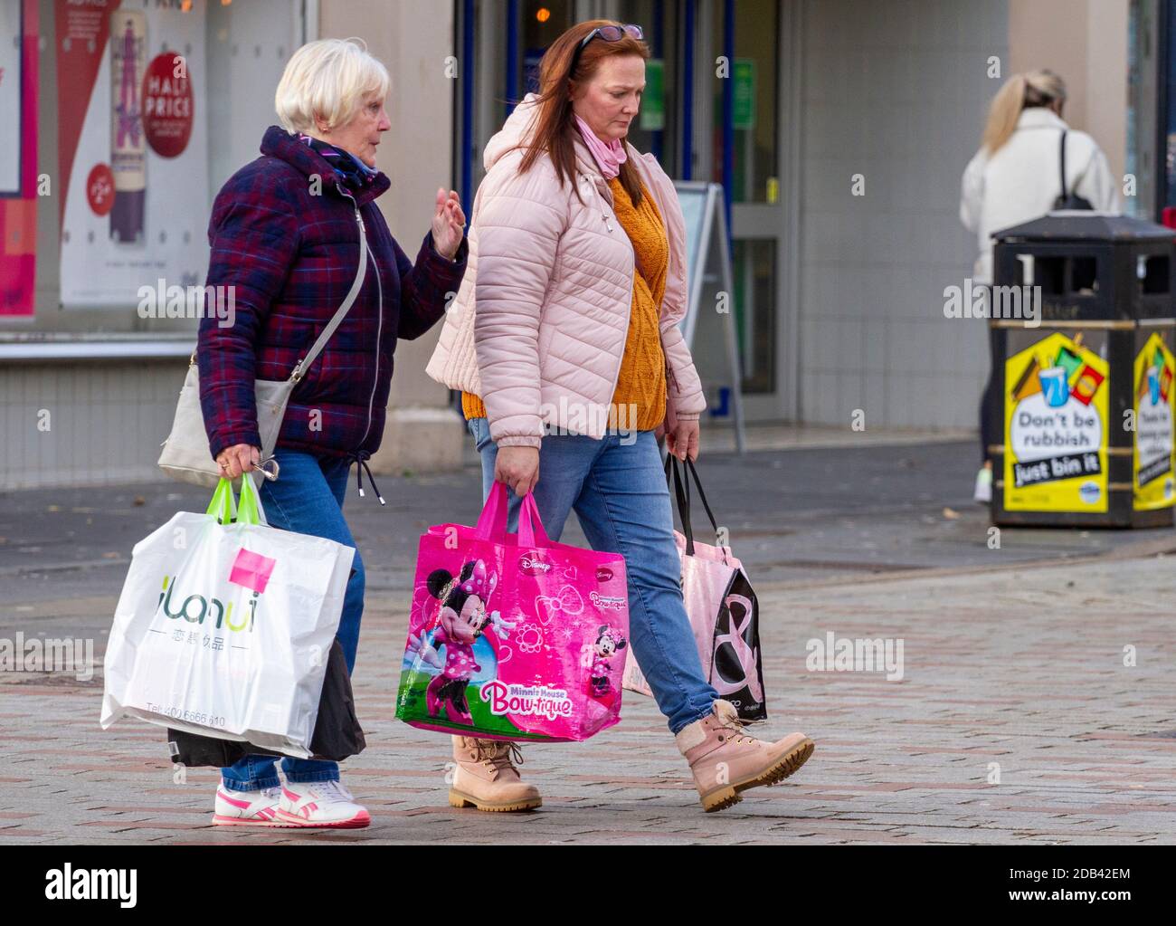 Dundee, Tayside, Scozia, Regno Unito. 16 Nov 2020. Notizie del Regno Unito Covid-19 Lockdown. Le persone che camminano per le strade di Dundee con pochi negozi di abbigliamento essenziali aperti dal livello 3 più rigoroso Covid-19 Lockdown restrizione è stato imposto. Due donne alla moda consapevoli delle linee guida di distanziamento sociale e l'uso di maschere facciali che camminano insieme mentre trasportano borse portariali di marca durante il suo shopping di Natale in centro città in un freddo e soleggiato pomeriggio di novembre. Credit: Dundee Photographics/Alamy Live News Foto Stock