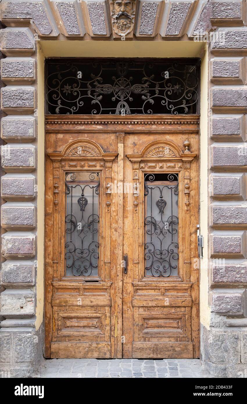Porta doppia in legno d'epoca con pannelli incorniciati e antichi tralicci in metallo riccamente decorati Foto Stock