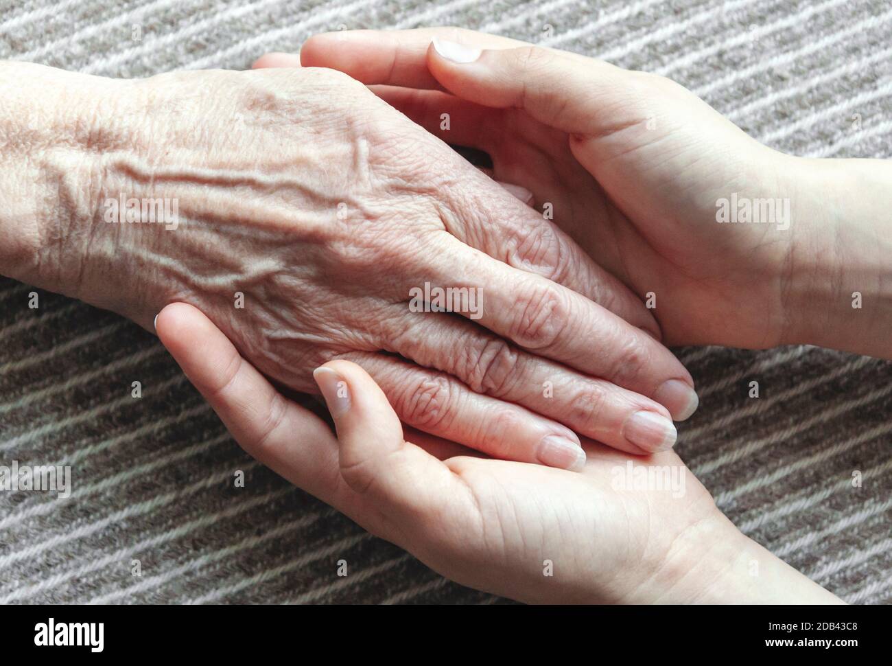 Le mani giovani che tengono la vecchia palma della donna, immagine closeup Foto Stock