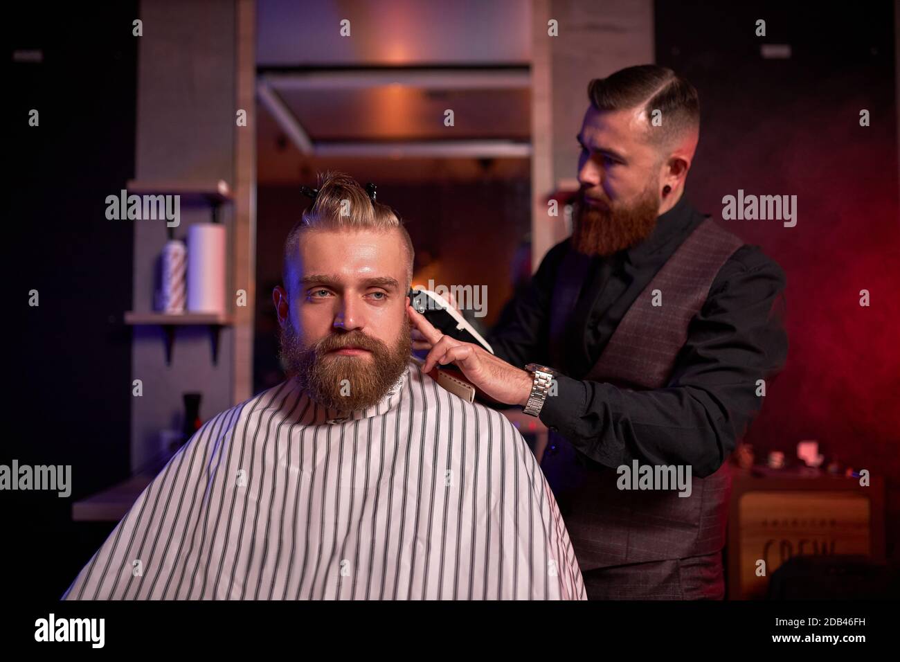 taglio capelli al parrucchiere, in salone. barbiere maschio tagli i capelli sulla testa del bel giovane cliente, il processo di creazione di acconciature per gli uomini da professionista Foto Stock