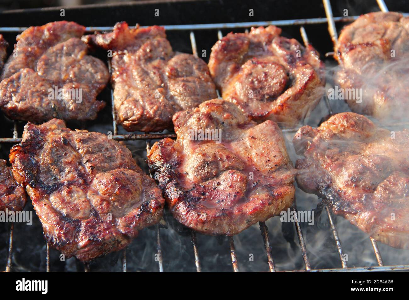 Cucinare pezzi di carne su fuoco closeup. Carne di maiale cotta. Pranzo barbecue all'aperto. Pezzi di carne di maiale alla griglia. Shashlik preparato su barbecue alla griglia Foto Stock