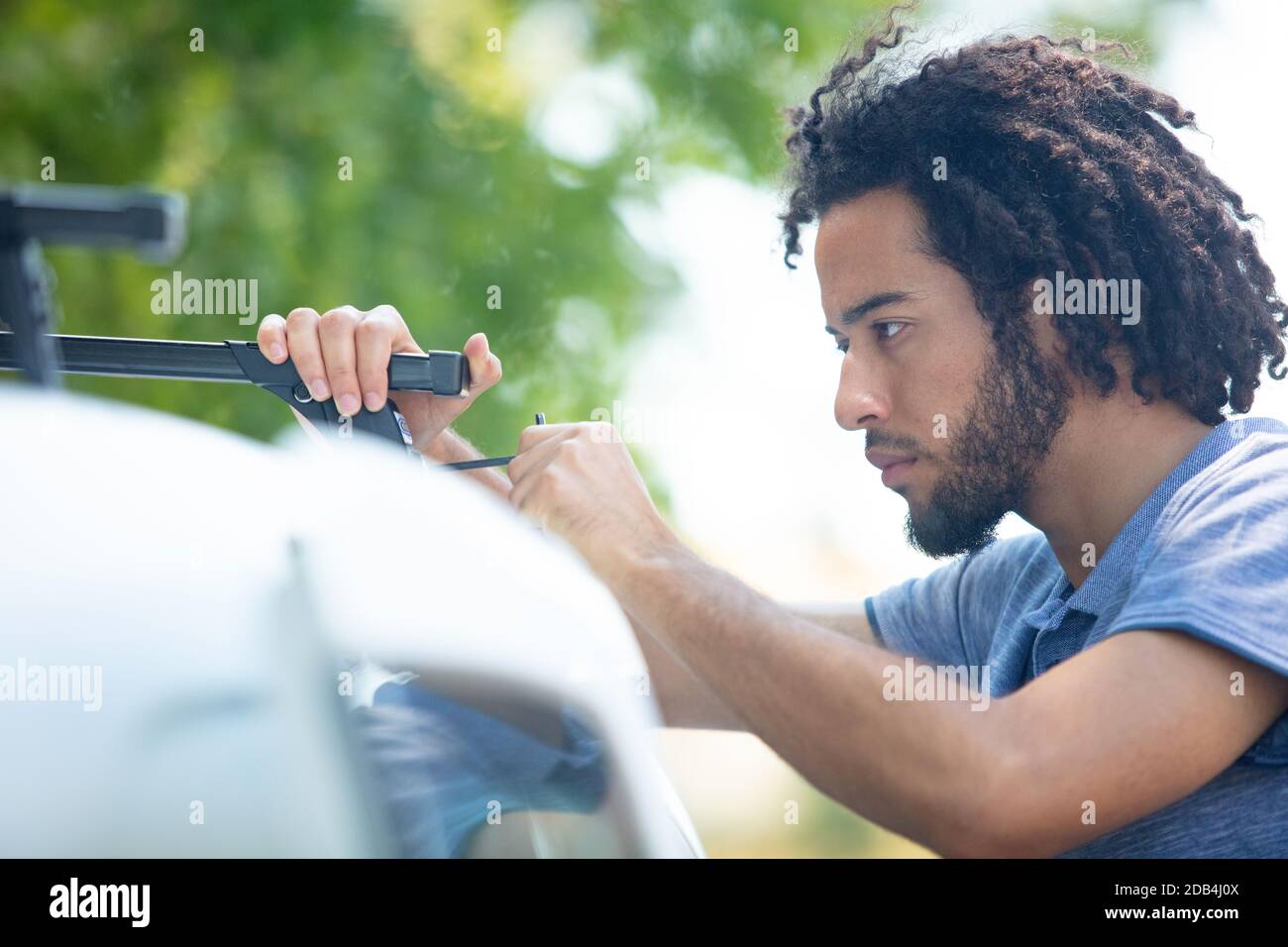 uomo che fissa le barre del tetto sulla sua auto Foto Stock