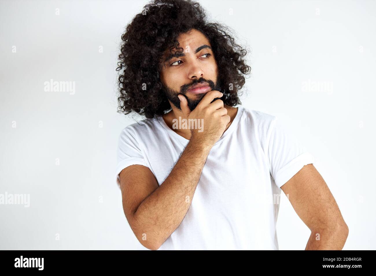 il maschio bearded premuroso è nella contemplazione, il ragazzo bello nell'usura casual che guarda via, isolato sopra sfondo bianco Foto Stock
