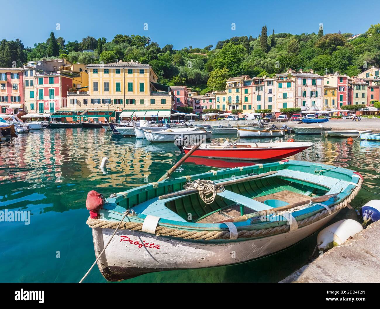 Portofino, la provincia di Genova, Liguria, Riviera Ligure, Italia. Le barche nel porto con il villaggio dietro. Foto Stock