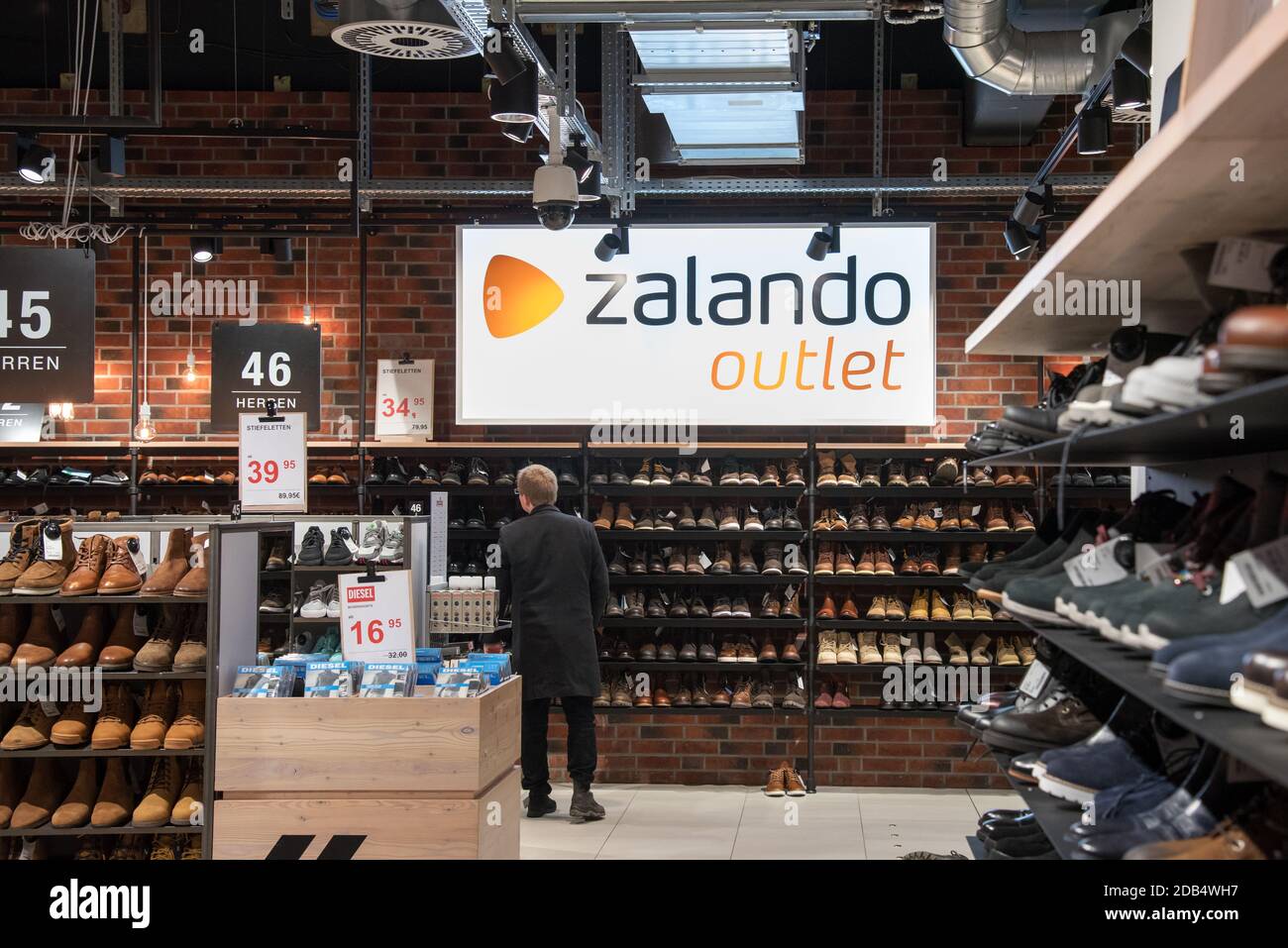 Il cliente all'interno del negozio outlet Zalando, visto dalla schiena,  guarda le scarpe sugli scaffali del negozio al dettaglio Foto stock - Alamy