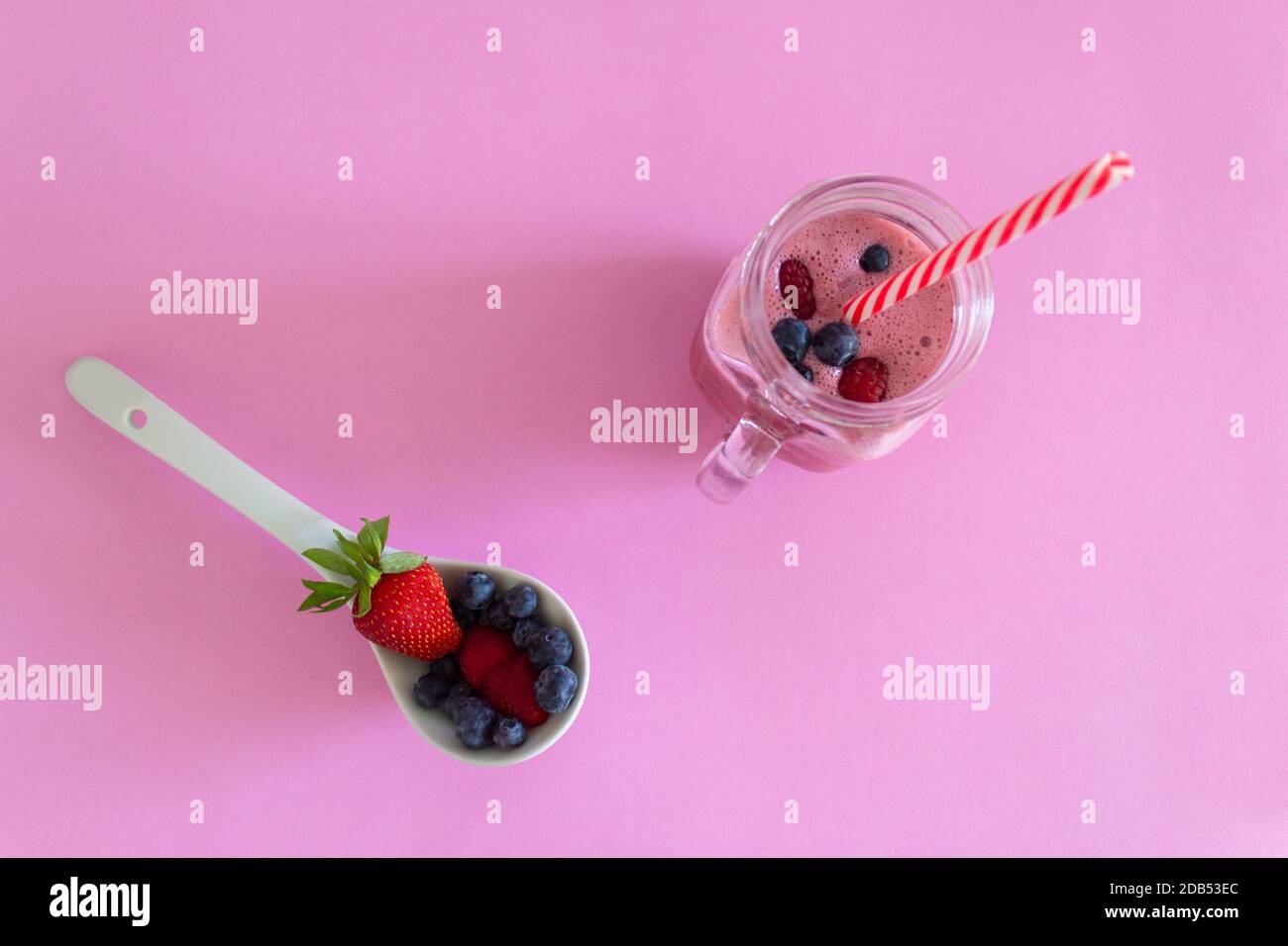 Vista dall'alto di fragole e frutti di bosco Smoothie, su sfondo rosa. Succo di frutta naturale, sano disintossicazione alimentare e concetto di bevanda. Foto Stock