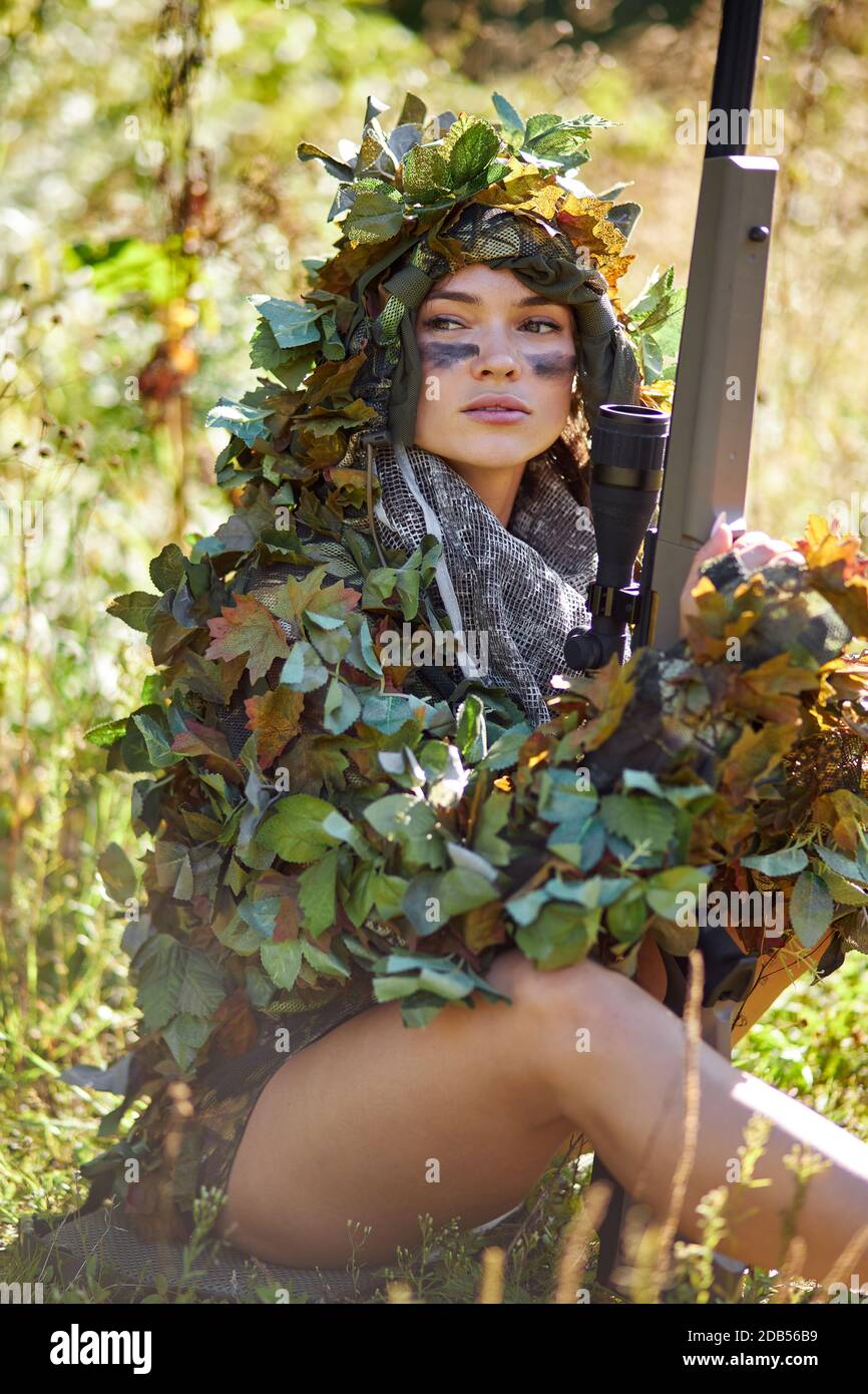 giovane caucasica intelligente cacciatore di cervi in uniforme verde con travestimento e fucile nella foresta, è appassionato di caccia in natura, forte e impavido Foto Stock