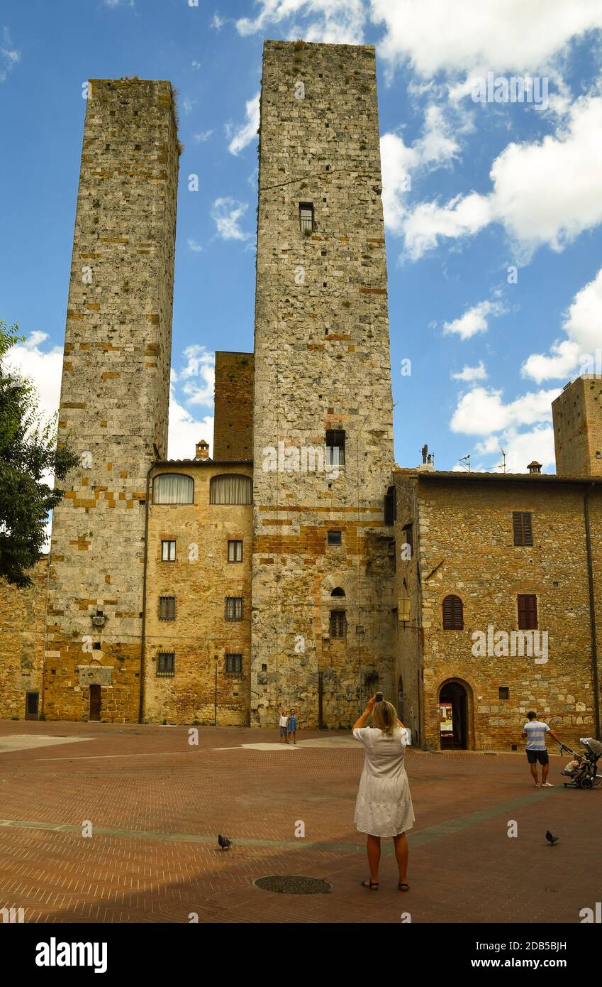 Torri dei Salvucci, torri gemelle medievali nel centro storico di San Gimignano, patrimonio dell'umanità dell'UNESCO, con turisti in estate, Siena, Toscana, Italia Foto Stock
