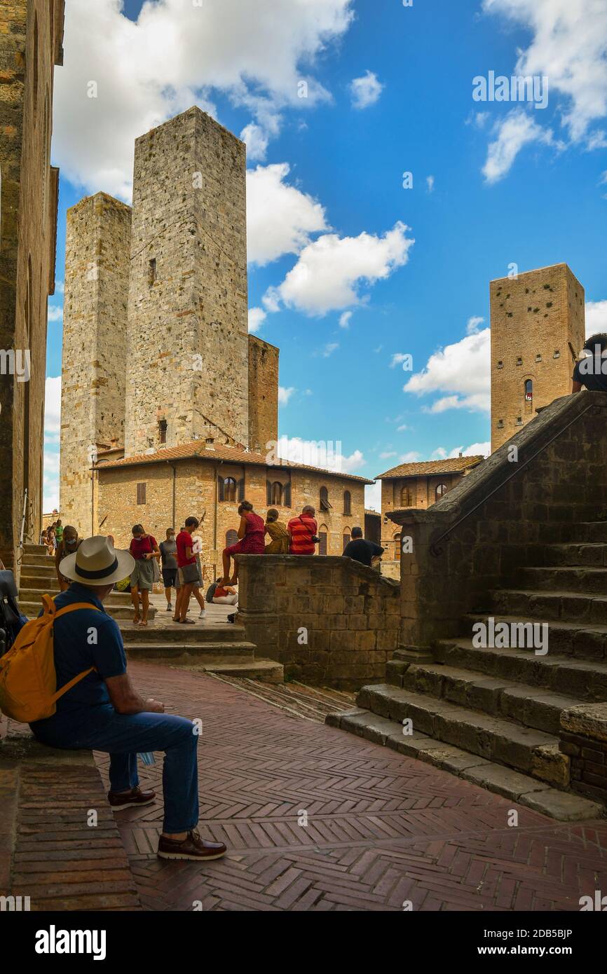 Turisti in Piazza Duomo con torri gemelle Torri dei Savucci, Torre Pettini e Torre Chigi nella città medievale di San Gimignano, Toscana, Italia Foto Stock
