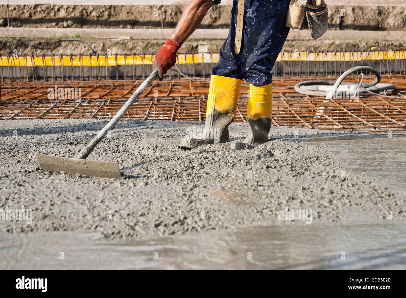 muratore al lavoro su un cantiere durante la posa di calcestruzzo per costruire le fondamenta di una casa Foto Stock