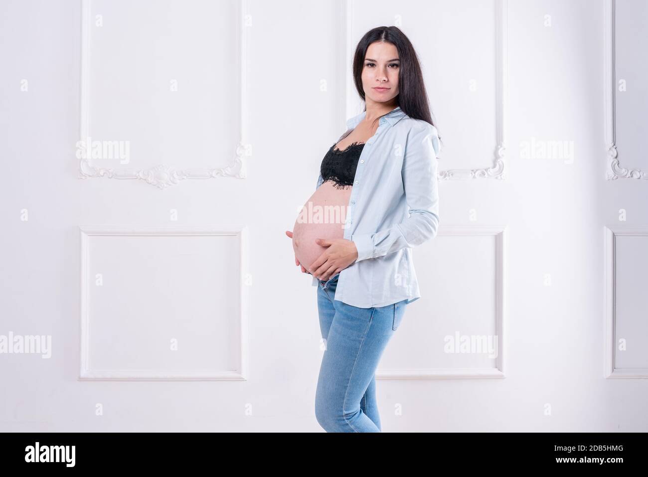 Felice ragazza incinta in jeans e camicia senza bottoni Foto Stock