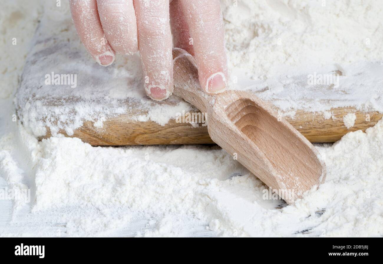 un semplice cucchiaio di legno con farina di grano durante la cottura, su un tavolo da cucina in campagna Foto Stock