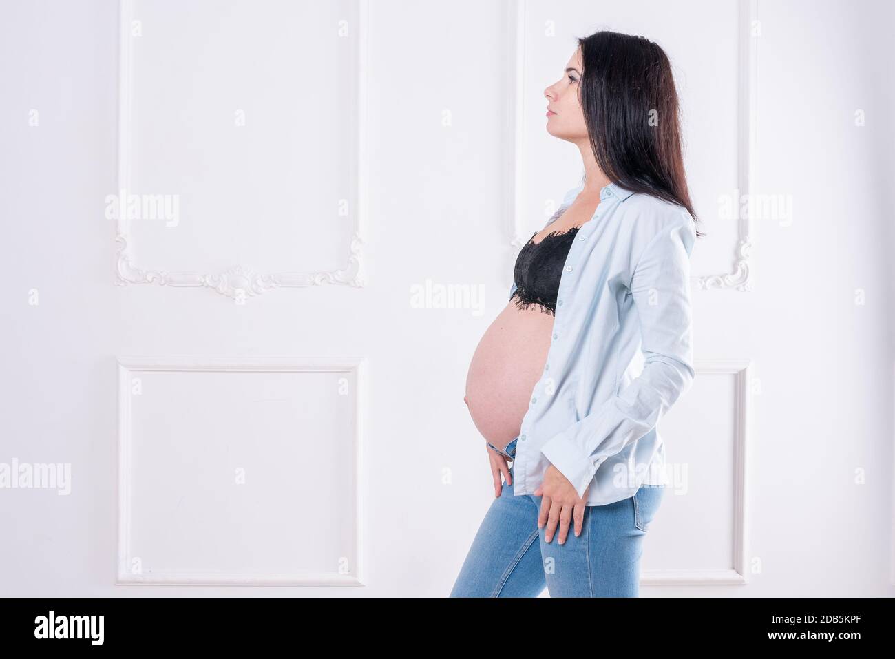 Felice ragazza incinta in jeans e camicia senza bottoni Foto Stock