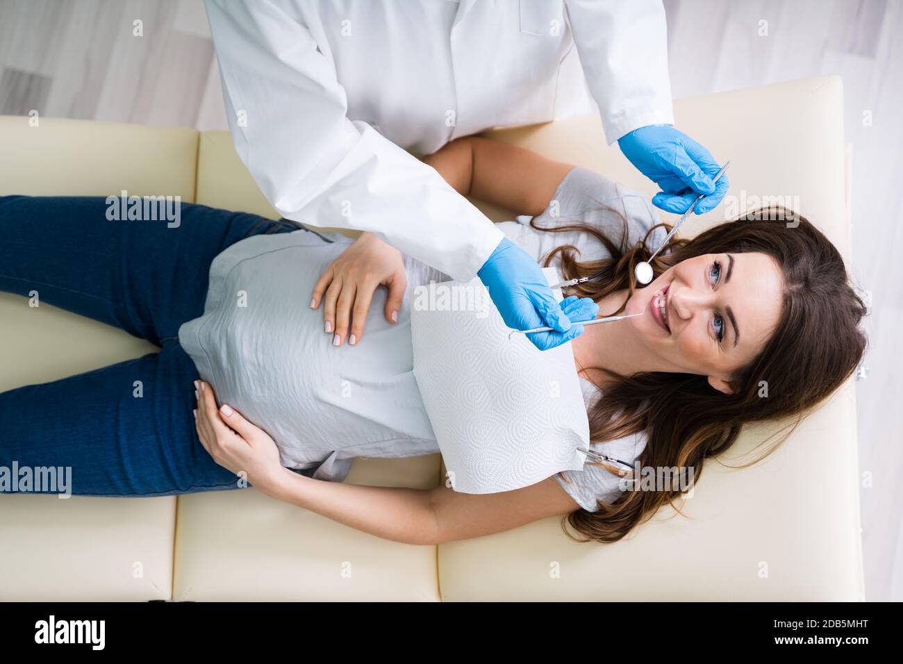 Un maschio di dentista il trattamento di denti della giovane donna incinta paziente sdraiato in clinica Foto Stock