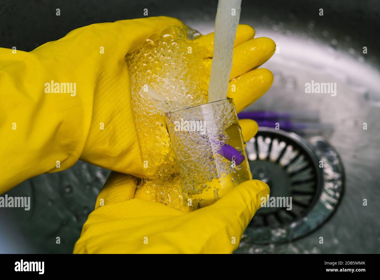 Lo scienziato sta conducendo la ricerca. Le mani in guanti protettivi gialli trattengono il pallone. Esperimento chimico in laboratorio. Medico nel Foto Stock