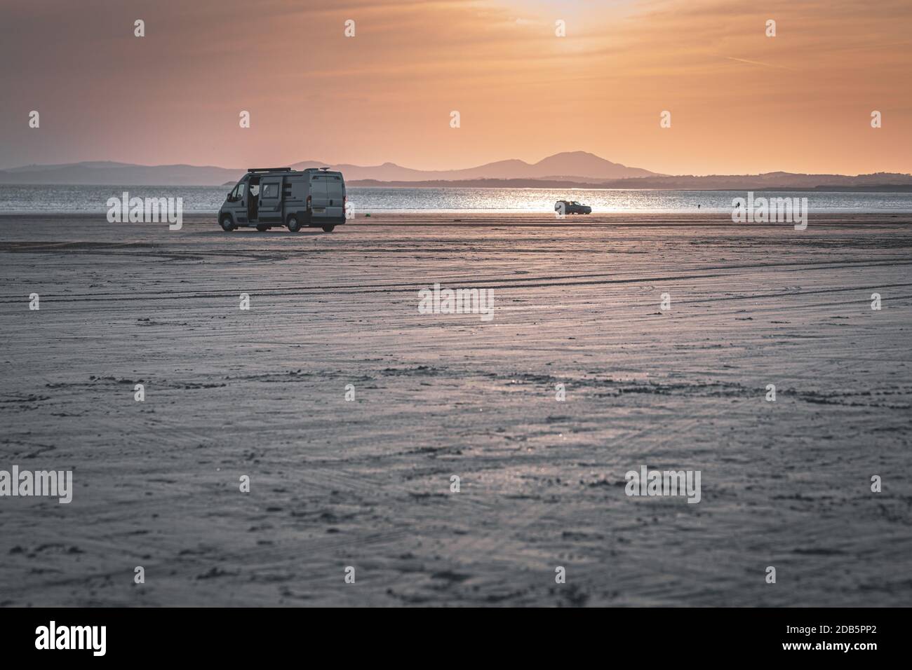 Camper parcheggiato sulla spiaggia di Black Rock Sands al tramonto nel Galles del Nord, Regno Unito Foto Stock