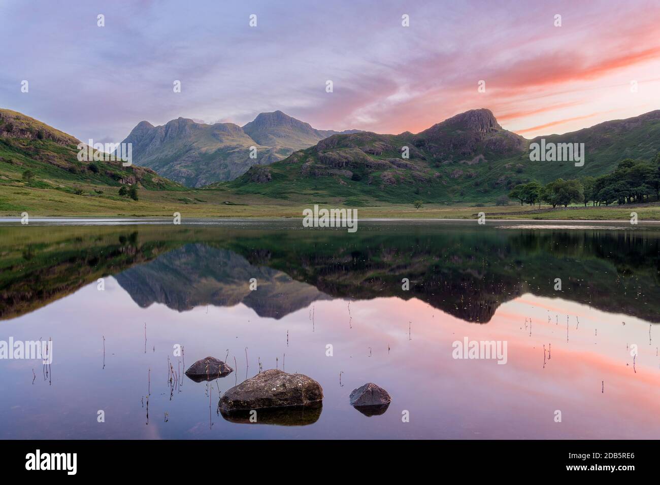 Riflessi chiari di montagne in acqua a Blea Tarn nel Distretto dei Laghi Inglese all'alba. Foto Stock