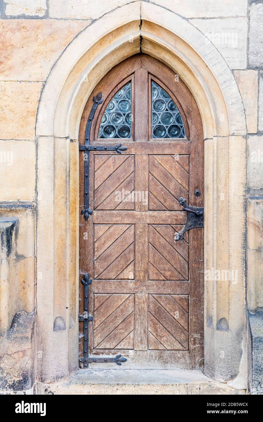 Portale d'ingresso in pietra storica con arco a punta. Finiture delle portiere anteriori e esterne marroni e stagne e finestrini in piombo Foto Stock
