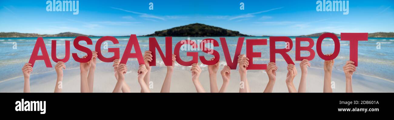 People Hands Holding colorato tedesco parola Ausgangsverbot significa Curfew. Oceano e Spiaggia come sfondo Foto Stock