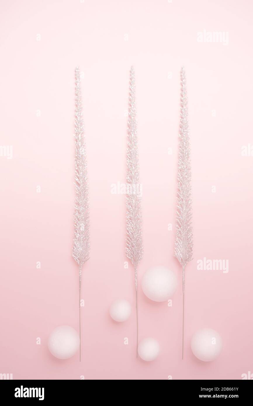 Decorazioni natalizie brillanti alberi di Natale e palline bianche su sfondo rosa pastello. Concetto invernale di Capodanno. Disposizione piatta, vista dall'alto, spazio per la copia. Verticale. Foto Stock