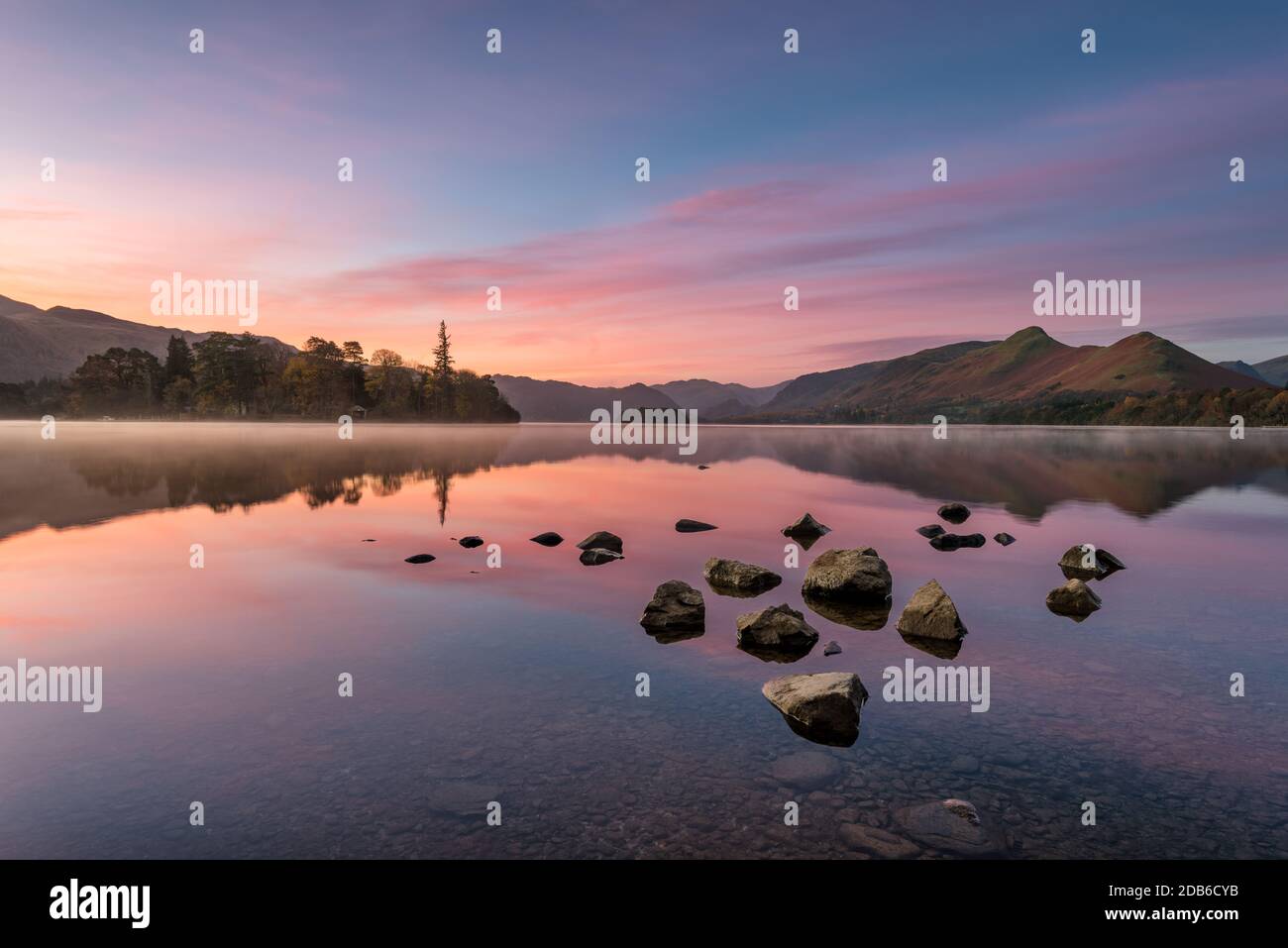 Bella rosa e viola prima dell'alba sorgere del sole con riflessi specchiati nel lago. Preso a Derwentwater nel distretto inglese del lago. Foto Stock