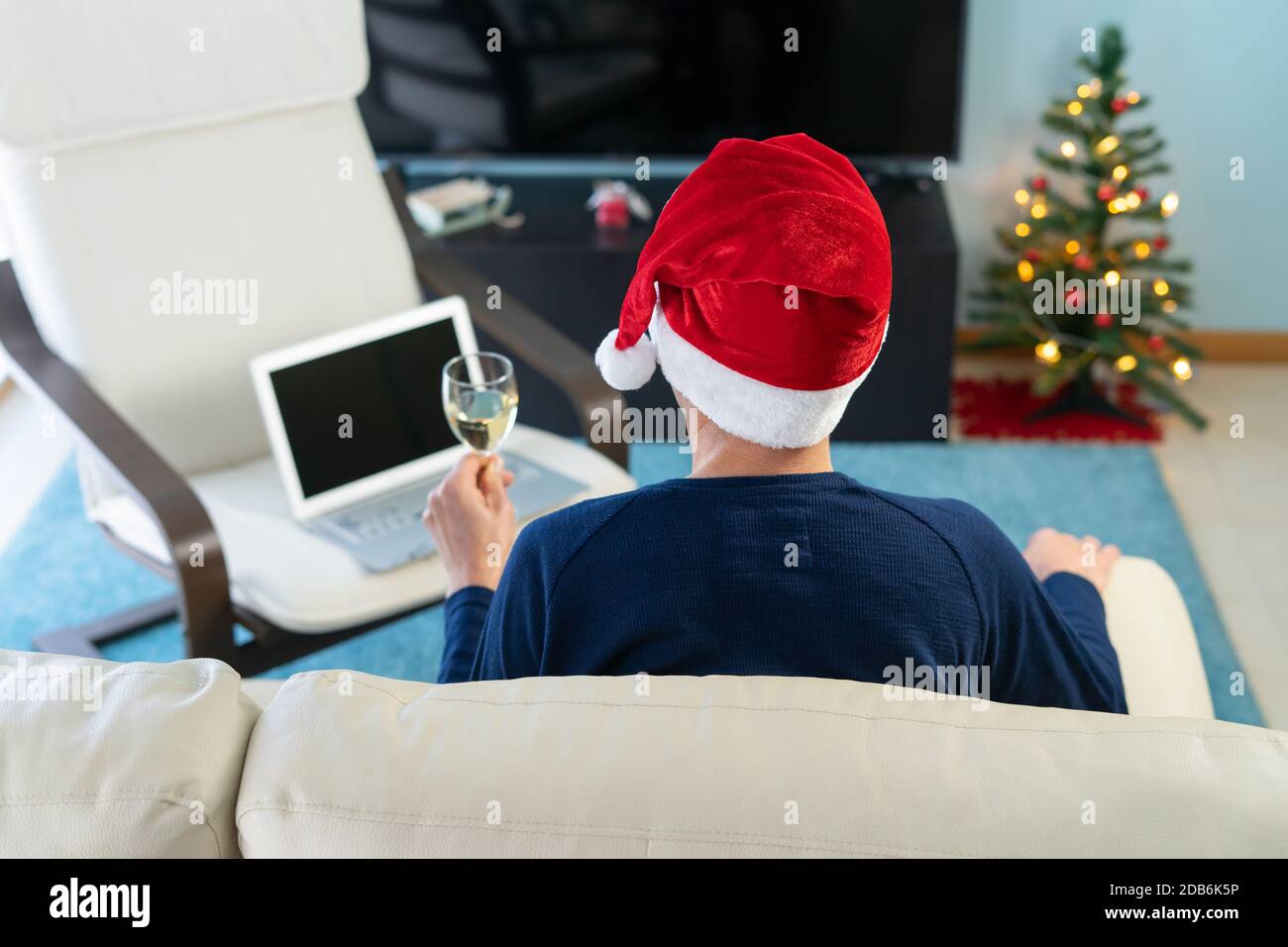 Uomo con cappello di Natale che tostano di fronte al computer. Concetto di tecnologia e confinamento. Foto Stock