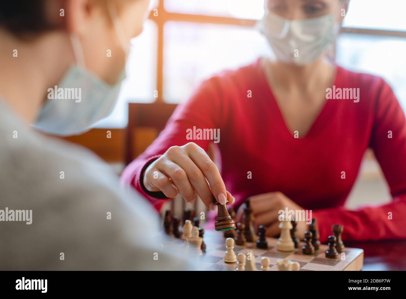 Famiglia che gioca giochi da tavolo durante il coprifuoco movimento pezzi scacchi, primo piano Foto Stock