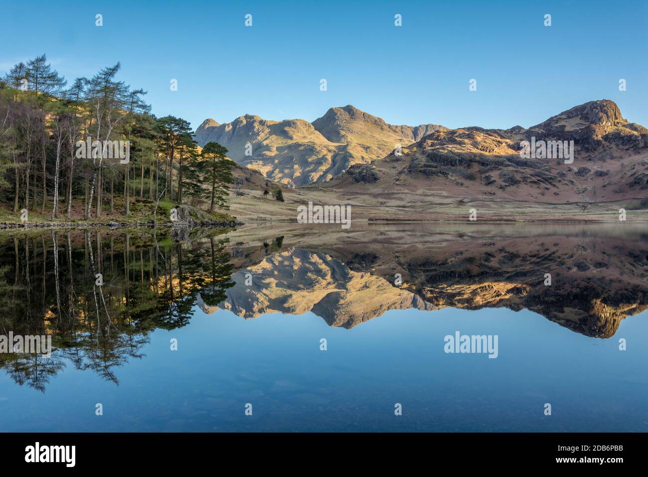 Riflessi chiari perfetti nel lago dei Langdale Pikes a Blea Tarn, nel Distretto dei Laghi Inglese, con cielo blu chiaro in una mattinata soleggiata. Foto Stock