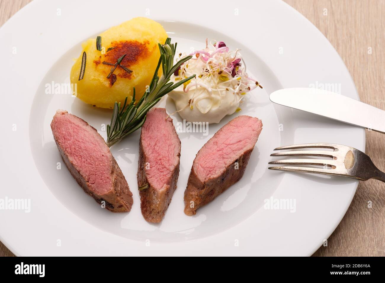 Sella di carne di agnello con patate fritte su una piastra Foto Stock