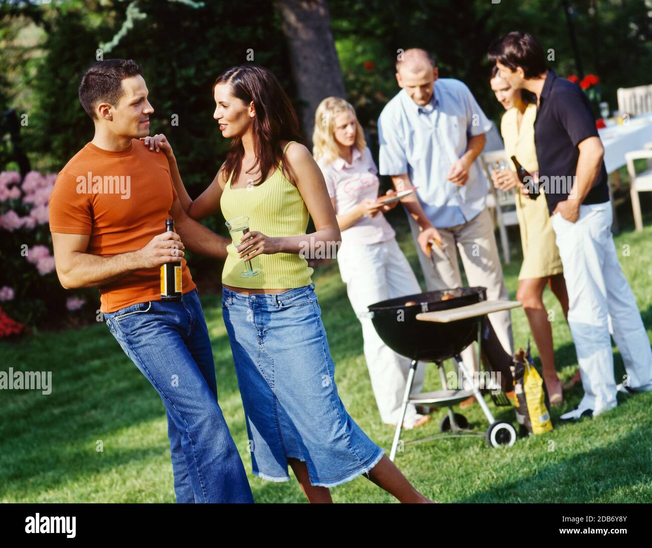 i giovani amichevoli che mangiano e bevono si riuniscono ed hanno divertimento in giardino con barbecue party Foto Stock