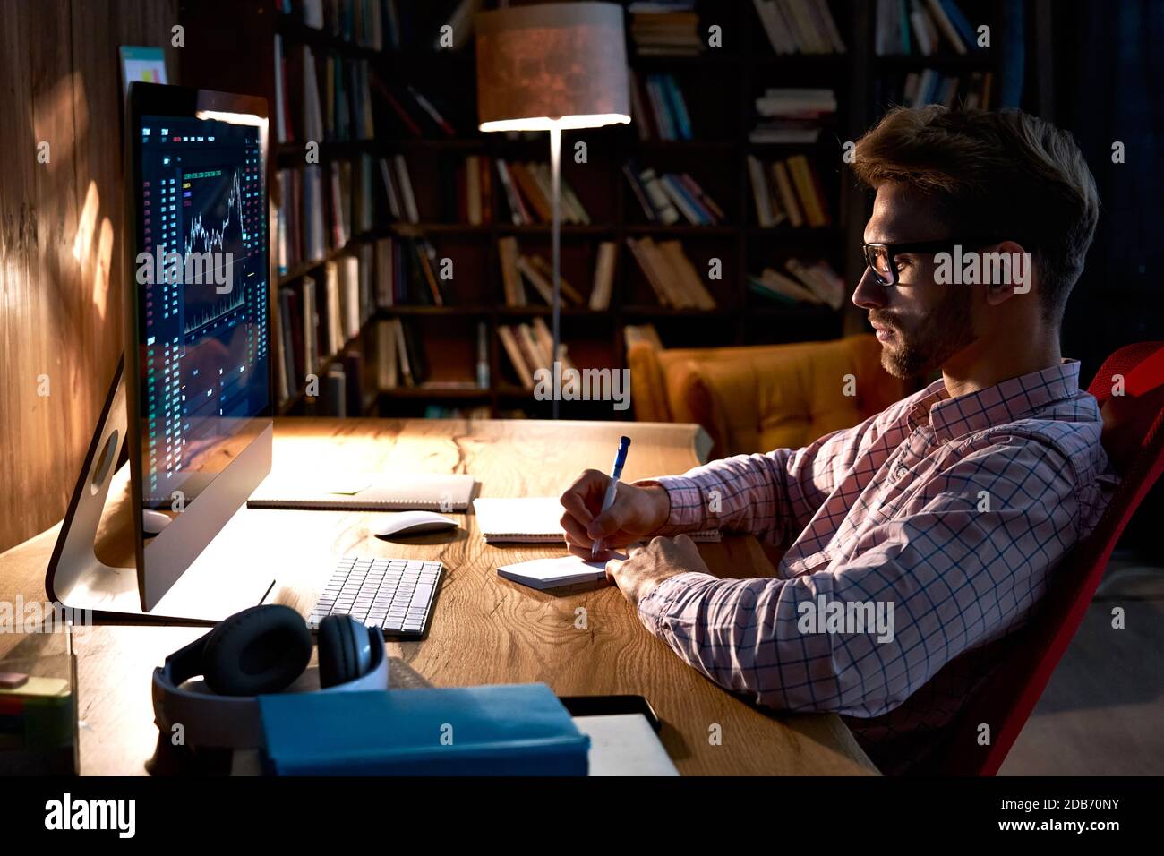 Uomo d'affari trader che osserva il pc che analizza i dati di trading di grafico finanziario. Foto Stock