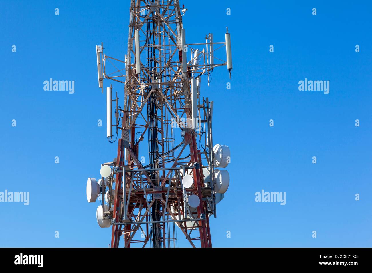 primo piano dell'albero delle telecomunicazioni che mostra varie antenne e piatti contro il cielo blu chiaro Foto Stock